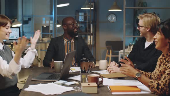 Colleagues Speaking and High Fiving at Night Business Meeting