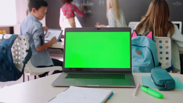 Laptop Computer Blank Empty Green Mockup Screen on School Desk in Classroom