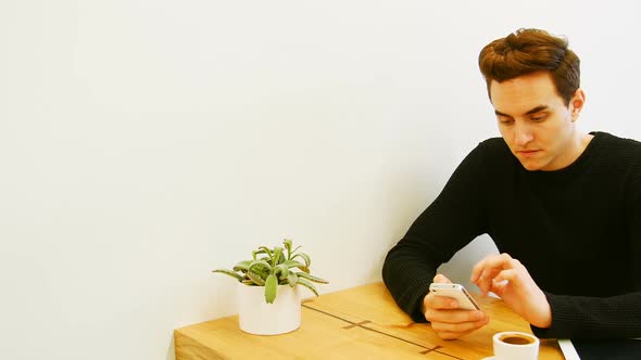 Man using mobile phone while having cup of coffee