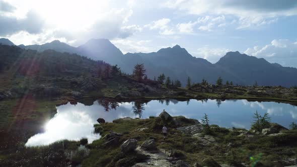 Moving Forward Above Clear Blue Lake and Tent Camp in Sunset Summer Day