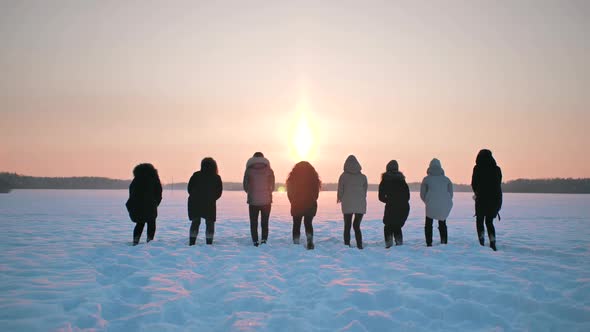 A Group of Girls Friends are Jumping and Throwing Snow Up at Sunset