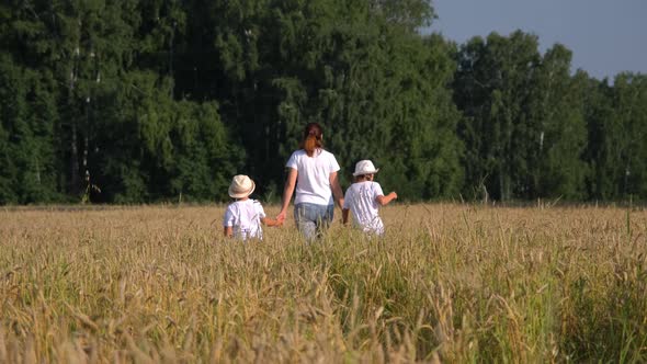 Mother with Children Walking in a Wheat Field