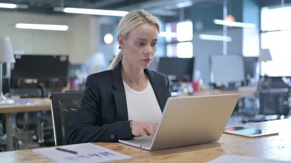 Serious Businesswoman Working on Laptop in Office
