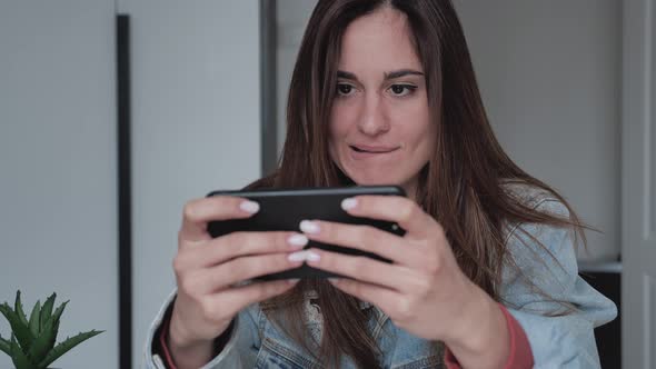 Closeup a Young Woman in a Denim Jacket Plays Games on Her Smartphone She Passed the Level and