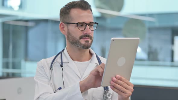 Middle Aged Male Doctor Browsing Internet on Tablet
