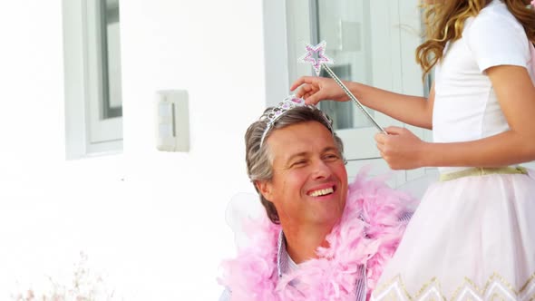 Daughter in angel costume putting crown on father head 4k