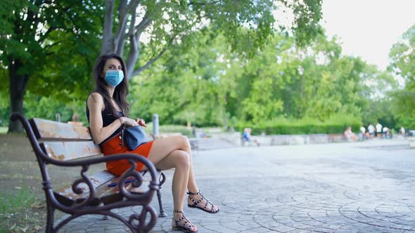 Brunette Woman Wearing Protective Face Mask in the Park. Social Distancing in the Public