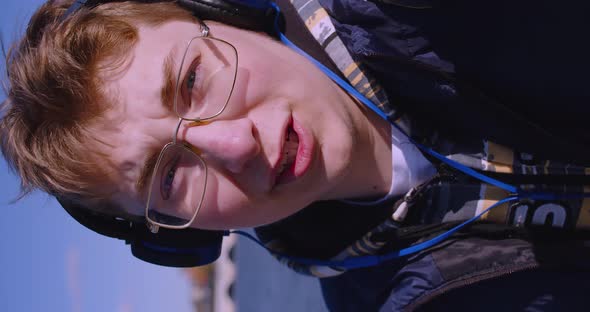Teenage Blogger in Headphones During an Online Video Broadcast He Holding the Camera at Arm's Length