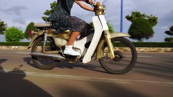 Woman Riding Motorcycle Along Highway Road in Slow Motion with Summer Dress