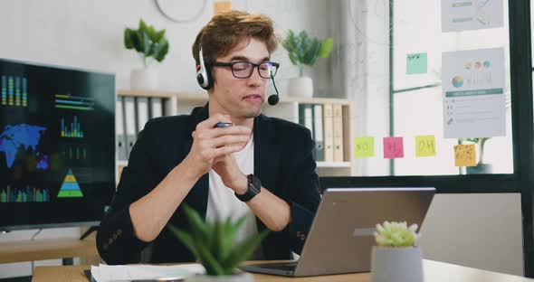 Guy in Headset Holding Online Meeting on Laptop with Colleagues and Giving them Advices