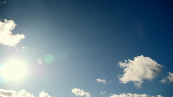 Sun Moves On Blue Sky. Lens Flare. Sunbeam Through White Clouds. Time Lapse