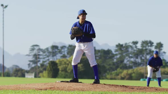 Caucasian female baseball player wearing glasses pitching ball on baseball field