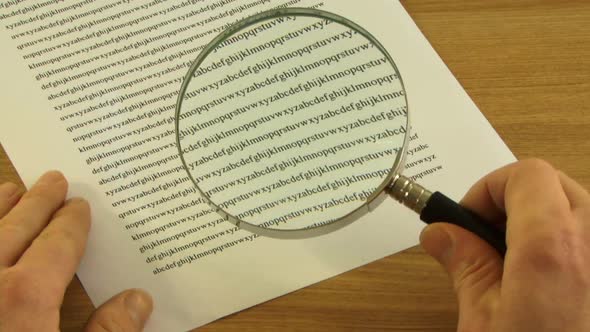 Male picking up Magnifying Glass to look at small print in contract