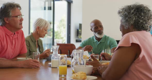 Happy senior diverse people having breakfast at retirement home