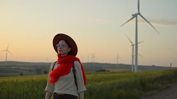 Young woman with a red scarf near a farm with alternative energy windmills