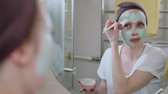 American Woman is Doing Cosmetic Procedure for Face While Standing in Home Bathroom Spbas