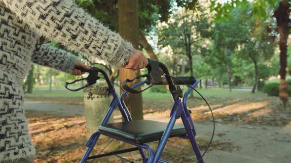 Old Hunched Over Woman Strolls Using Rollator Walkers