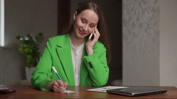 Woman Talks to Client Via Mobile Phone Writing Notes