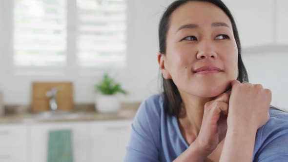 Portrait of happy asian woman sitting in kitchen