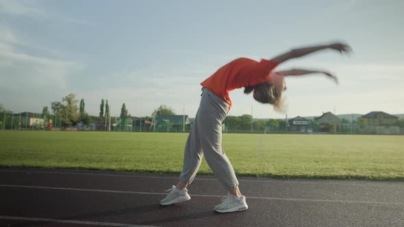 Young Beautiful Girl in Sweatpants and an Orange Tshirt Goes in for Sports