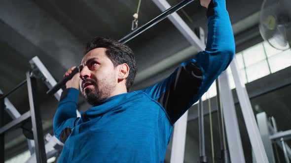 4K Caucasian man bodybuilder pulling weight lifting machine at gym.