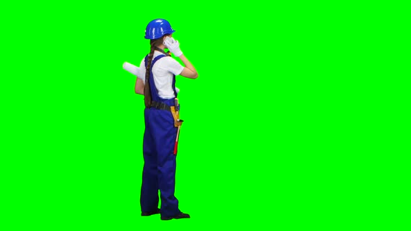 Builder Is Standing and Talking on the Phone with a Drawing in Her Hands. Green Screen