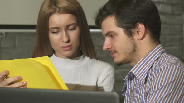 Two Young Business People Discussing Documents at the Office