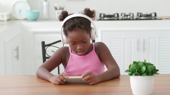 Charming Little Girl Wearing Wireless Headphones Using Mobile Phone Listens to the Music and