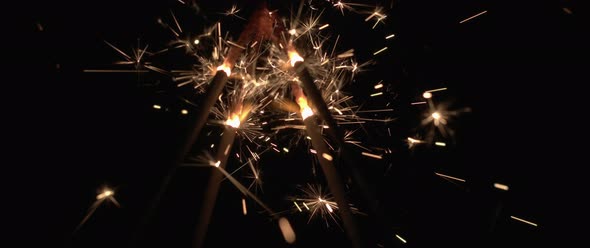 Sparklers burning down in the dark background in slow motion. 