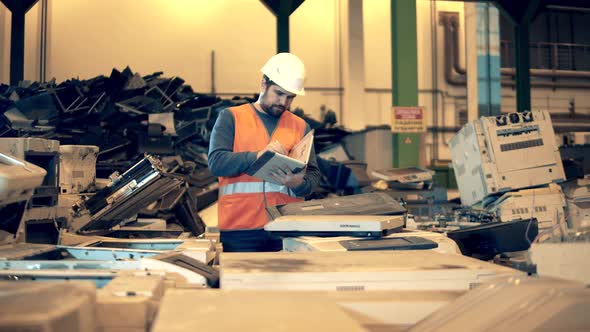 Male Employee is Making Notes in the Indoors Dumpsite