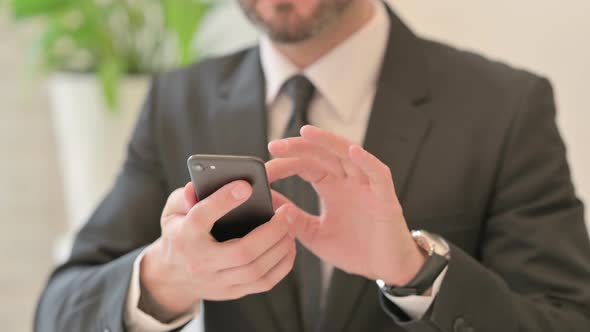 Close Up of Middle Aged Businessman Celebrating Success on Smartphone