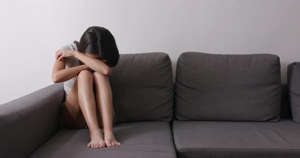 Woman crying sitting on sofa in living room