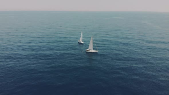 Aerial View of Two Yachts in the Ocean Silhouettes of Swimming People Next to Yachts