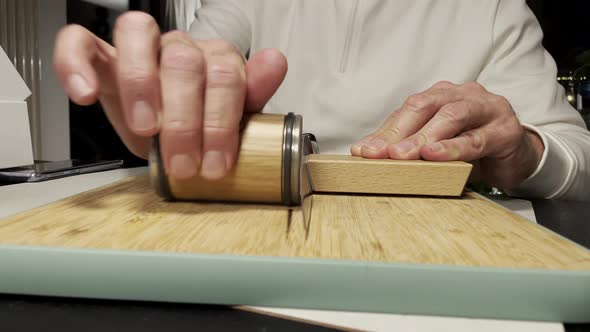 Male hand Sharpening Knife with modern grindstone on wooden board. Man preparing professional tools