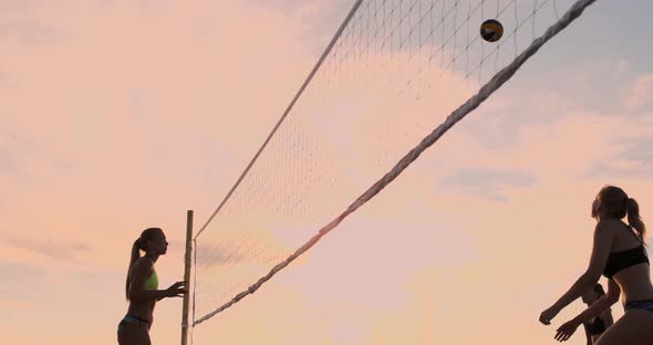 Young Female Volleyball Players Pass and Spike the Ball Over the Net on a Sunny Summer Evening. Fit