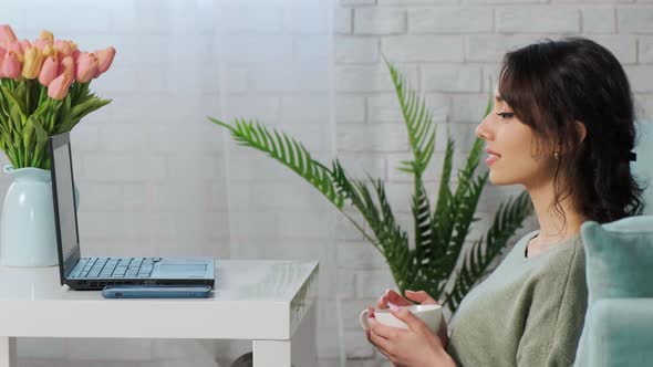 Girl Sits on Floor Carpet and Use Computer to Watch Movie and Drink Tea