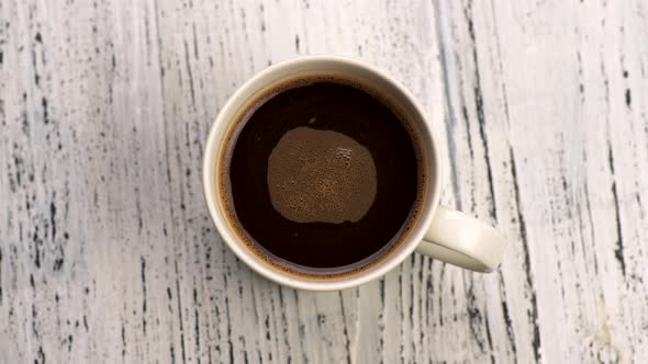 Brown Coffee with Bubbles in White Cup. Liquid Rotating in Cup. Top Down Close-up Shot