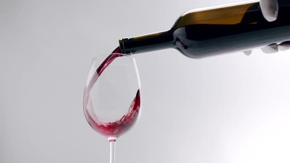 Pouring Black Red Wine From a Clear Glass Into an Glass on a White Background