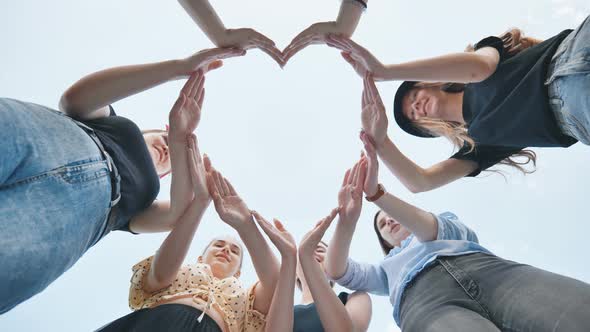 Girlfriends Girls Make a Heart Shape From Their Hands Against the Blue Sky