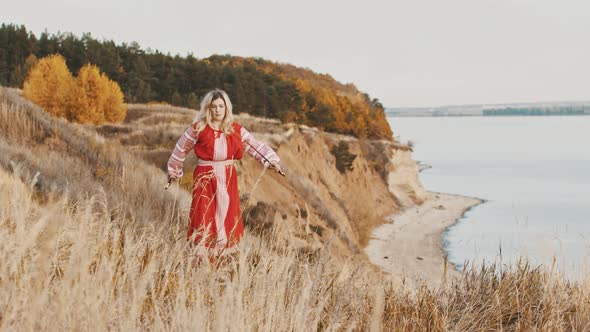 A Woman Warrior in National Dress Standing on the Edge of Hill with Two Swords and Wields Them