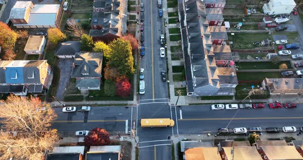 Tracking shot of yellow school bus driving through American urban city, residential community neighb