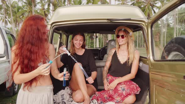 Happy Female Friends Blowing Bubbles while Vacationing on Coast of Bali