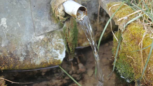 Close-up View of a Stream of Water Emerging From a Small Pipe Sticking Down Between Stones in Slow