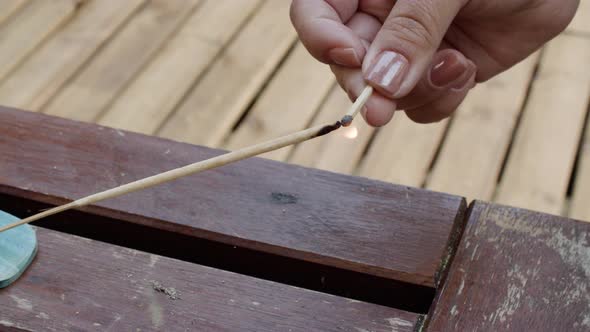 Closeup Shot of Hand Lighting Wooden Incense Stick with Match