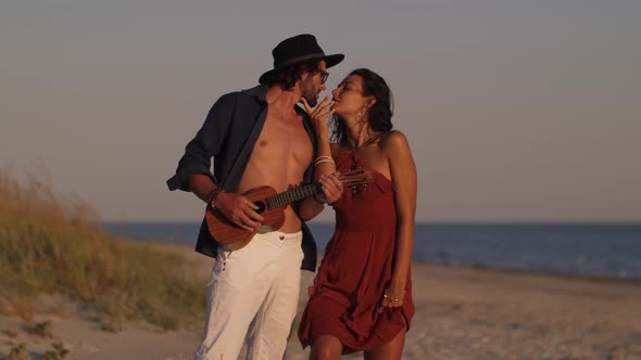 Couple in Love Playing Guitar and Dancing on the Beach