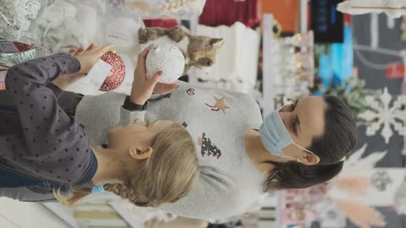 Woman in Face Mask and Daughter Do Xmas Shopping