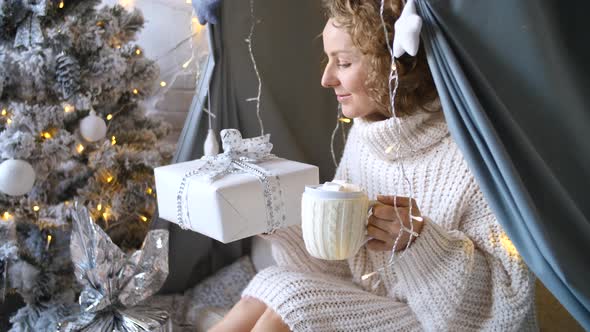Happy Woman Holds Hot Chocolate With Marshmallows And Christmas Gifts