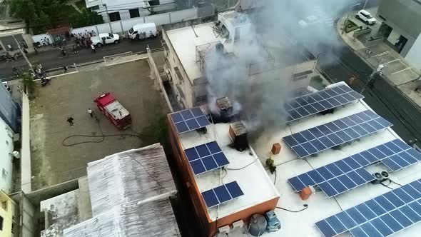 Aerial view of smoke rising from a building fire, with solar power panels on the roof, in Manila cit