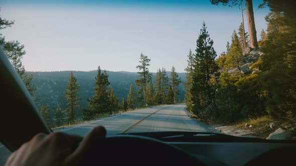 Beautiful First Person View of Male Hand Holding Car Steering Wheel Driving Along Mountain Road