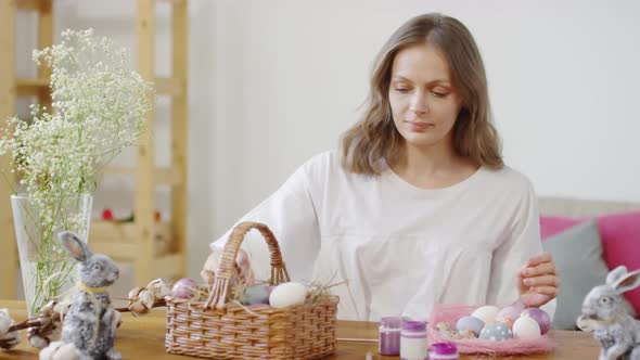 Woman Putting Easter Eggs into Basket